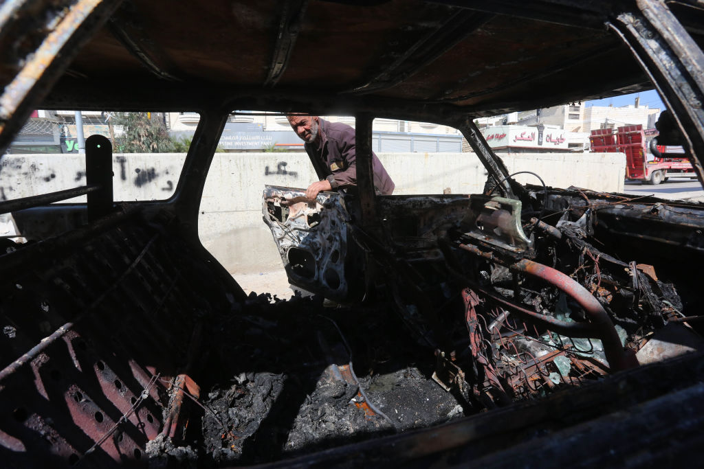 رجل فلسطيني يتفقد المركبات المحترقة التي أشعلها المستوطنون اليهود في بلدة حوارة في نابلس بالضفة الغربية في 28 مارس 2023. (تصوير نضال اشتية
