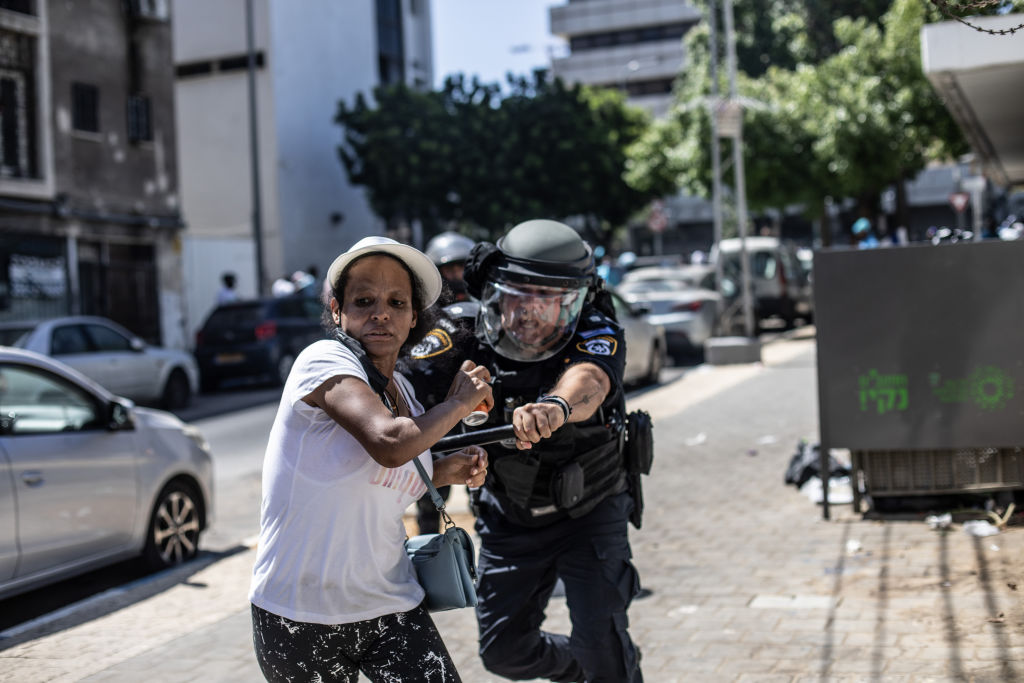 شرطي إسرائيلي يلاحق اريتيرية في تل أبيب، أثناء قمع التظاهرات - متظاهرون إيرتيريون في تل أبيب، هاجموا مركبة شرطة إسرائيلية - أحد المتظاهرين الإيرتيريين الذين تعرضوا للضرب في تل أبيب - Mustafa Alkharouf/Getty Images