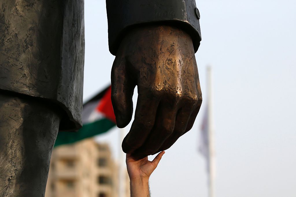 فلسطيني يمسك بيد مجسّم لنيلسون مانديلا في رام الله - ABBAS MOMANI/ Getty Images)
