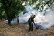 جندي إسرائيلي يطفئ حرائق تسببت بها صواريخ حزب الله على "كريات شمونة"