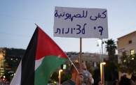 ناشط يساري يرفع شعار "كفى للصهيونية" خلال تظاهرة سياسية بمدينة حيفا. تصوير: (Activestills) 