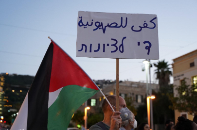 ناشط يساري يرفع شعار "كفى للصهيونية" خلال تظاهرة سياسية بمدينة حيفا. تصوير: (Activestills) 