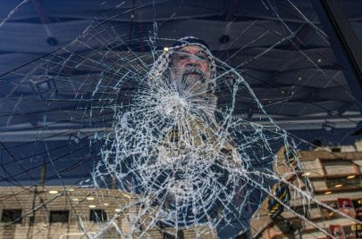 فلسطيني يقف أمام زجاج مهشّم جراء اعتداءات المستوطنين في حوارة جنوب نابلس - Nasser Ishtayeh/Getty Images 