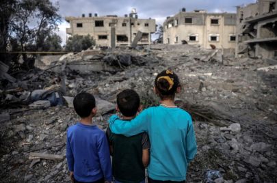 أطفال يقفون قبالة منازلهم المدمّرة جرّاء القصف الإسرائيلي الذي استهدف دير البلح - MOHAMMED ABED/ Getty 