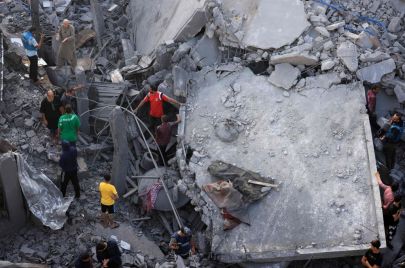 / أشخاص يتحققون من الأضرار الناجمة عن قصف إسرائيلي على مخيم المغازي للاجئين في دير البلح وسط قطاع غزة، في 5 تشرين الثاني (نوفمبر) 2023