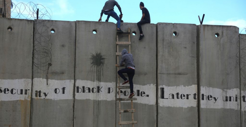فلسطينيون من الضفة يتسلّقون الجدار الإسرائيليّ الفاصل للوصول إلى القدس، والصلاة في المسجد الأقصى (عصام الريماوي - Getty - 2019) 