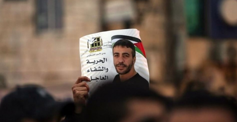 رفع صورة مطالبة بالإفراج عن الأسير ناصر أبو حميد، خلال مسيرة تضامن معه 