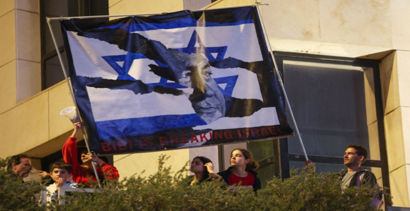 متظاهرون يحملون لافتة تشير إلى أن نتنياهو يتسبب بتمزيق (دولة إسرائيل) في مظاهرة في تل أبيب