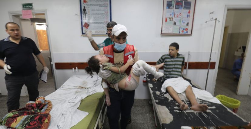 رجل يحمل طفلًا مصابًا في مستشفى رفح. تصوير عبد الرحيم خطيب