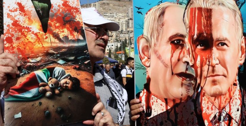 متظاهر يحمل صورة لرئيس الوزراء الإسرائيلي بنيامين نتنياهو والرئيس الأمريكي جو بايدن مرسومة باللون الأحمر لتقليد الدم، خلال مسيرة لدعم الشعب في قطاع غزة، في مدينة نابلس بالضفة الغربية المحتلة، في 26 أكتوبر 2026.