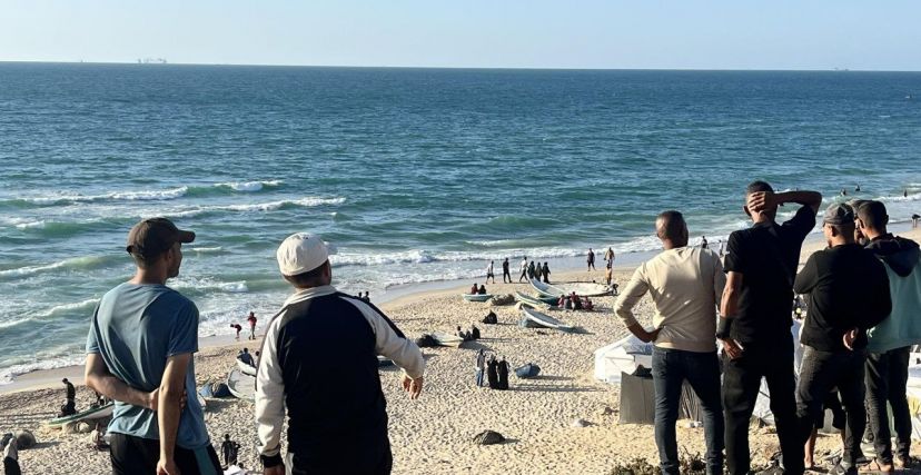 مواطنون يتابعون وصول سفن كبيرة قرب الميناء العائم قبالة شواطئ غزة. عبد الكريم السموني (الترا فلسطين)