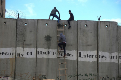 فلسطينيون من الضفة يتسلّقون الجدار الإسرائيليّ الفاصل للوصول إلى القدس، والصلاة في المسجد الأقصى (عصام الريماوي - Getty - 2019) 